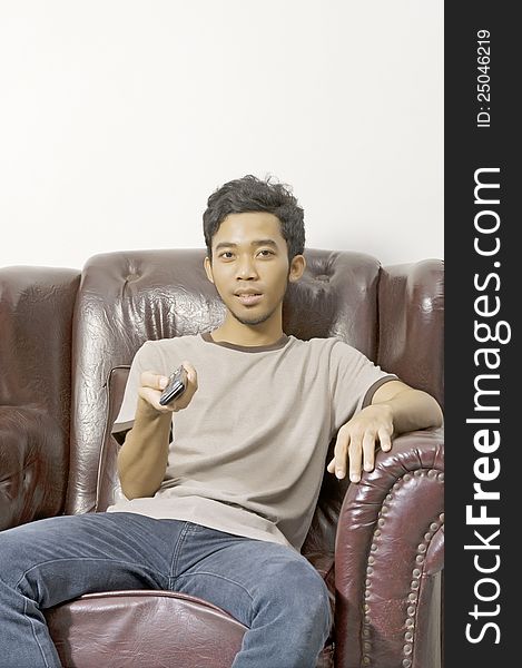 Young man watching tv from his couch and holding remote control