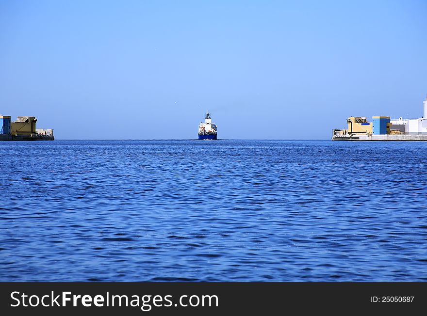 Panorama view with cargo ship moving from harbour to open sea. Panorama view with cargo ship moving from harbour to open sea