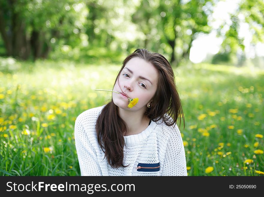 Beauty teenage girl with yellow dandelions in her mouth on green summer background. Beauty teenage girl with yellow dandelions in her mouth on green summer background