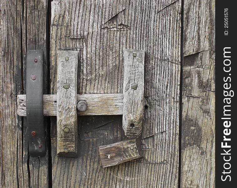 Close-up of an old and rustic door latch made of wood. Close-up of an old and rustic door latch made of wood.