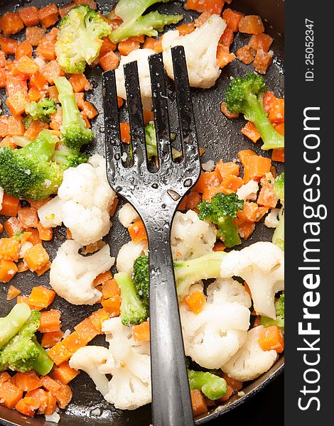 Serving of fresh chopped vegetables fried lightly in a metal skillet and served with a fork. Serving of fresh chopped vegetables fried lightly in a metal skillet and served with a fork