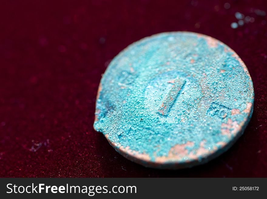Corroded Blue Coin on Red Velvet Background