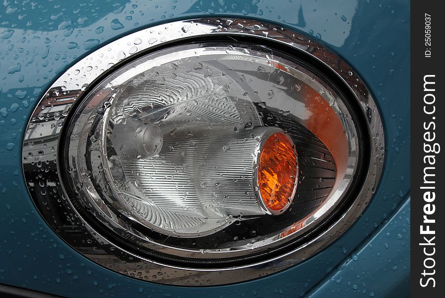 A headlight of elegant car just after a rain shower.