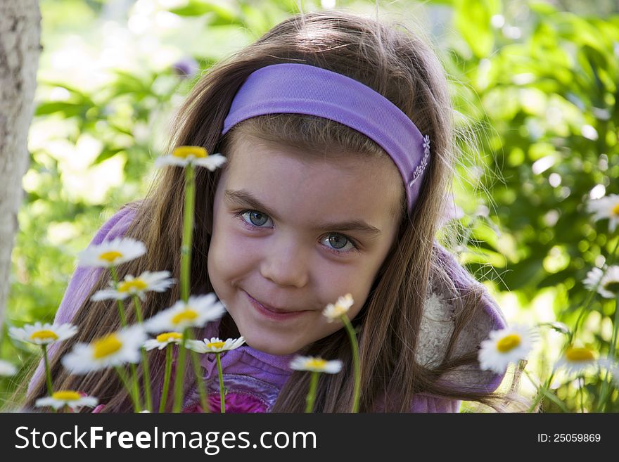 Beautiful little girl among camomiles in a garden. Beautiful little girl among camomiles in a garden