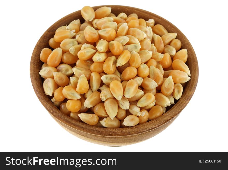 A wooden bowl full of dried yellow corn kernels, isolated on white background