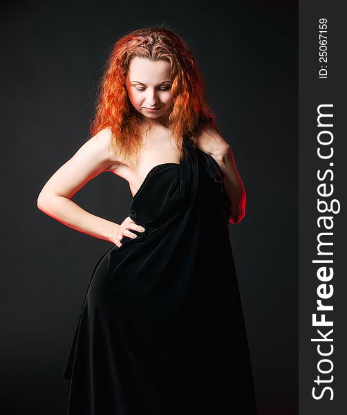 Redhead girl in black posing on a dark background