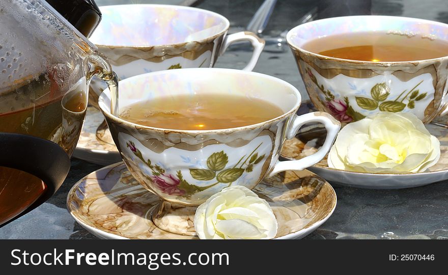 Pouring tea from porcelain tea-kettle into cup.