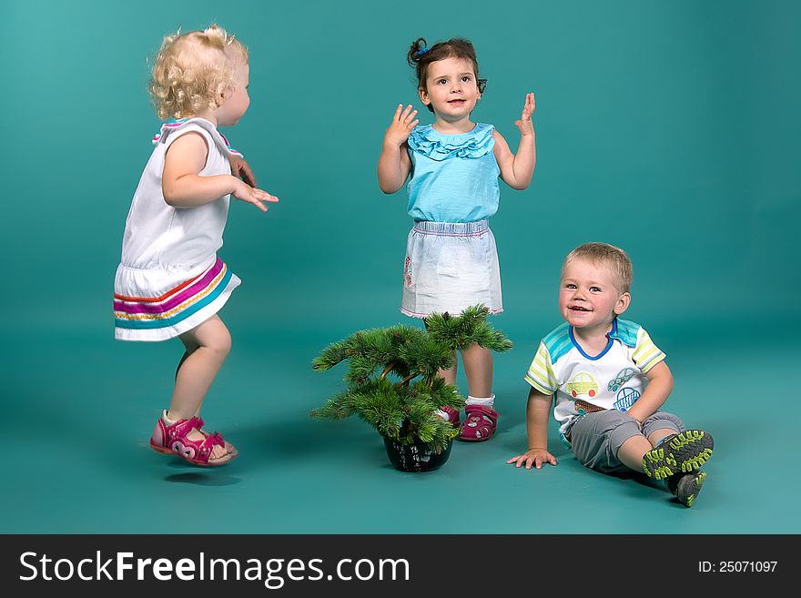 Three children playing on a turquoise background in studio