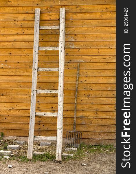 Leaning against a wooden ladder, ladder and forks perpendicular, working tools for farmers, ladder with six, two job aids at the stables with horses