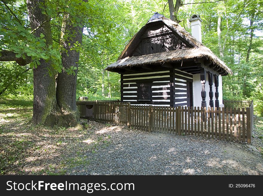 Preserved cottage with a roof of straw surrounded by a fence, timbered cottage in the woods. Preserved cottage with a roof of straw surrounded by a fence, timbered cottage in the woods