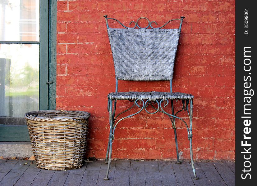 Pretty metal chair and handmade basket sitting on the front porch of an old red brick house. Pretty metal chair and handmade basket sitting on the front porch of an old red brick house.