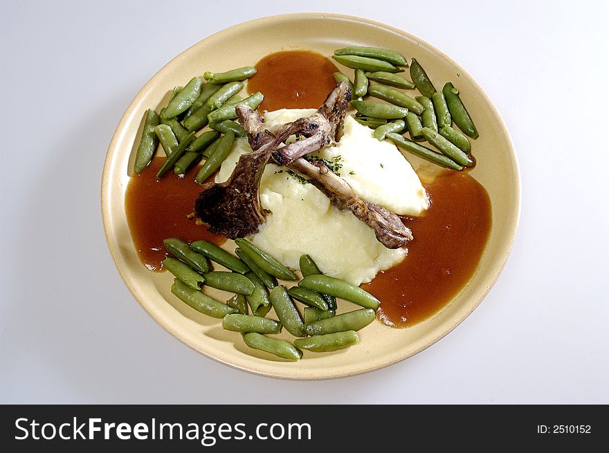 Picture of pork ribs with sauce, stewed vegetables and mashed potatoes.