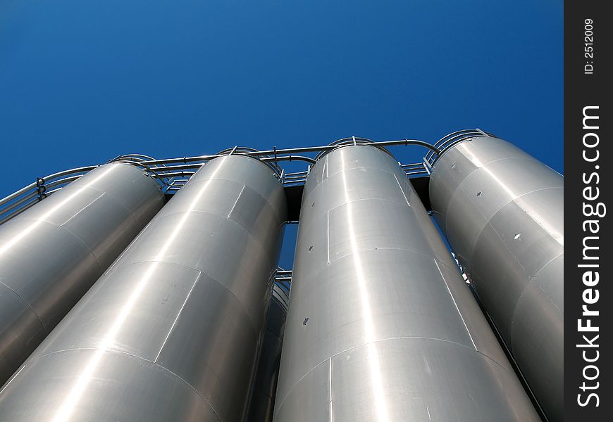 Tanks of silvery color, are photographed on a background of the blue sky. Tanks of silvery color, are photographed on a background of the blue sky
