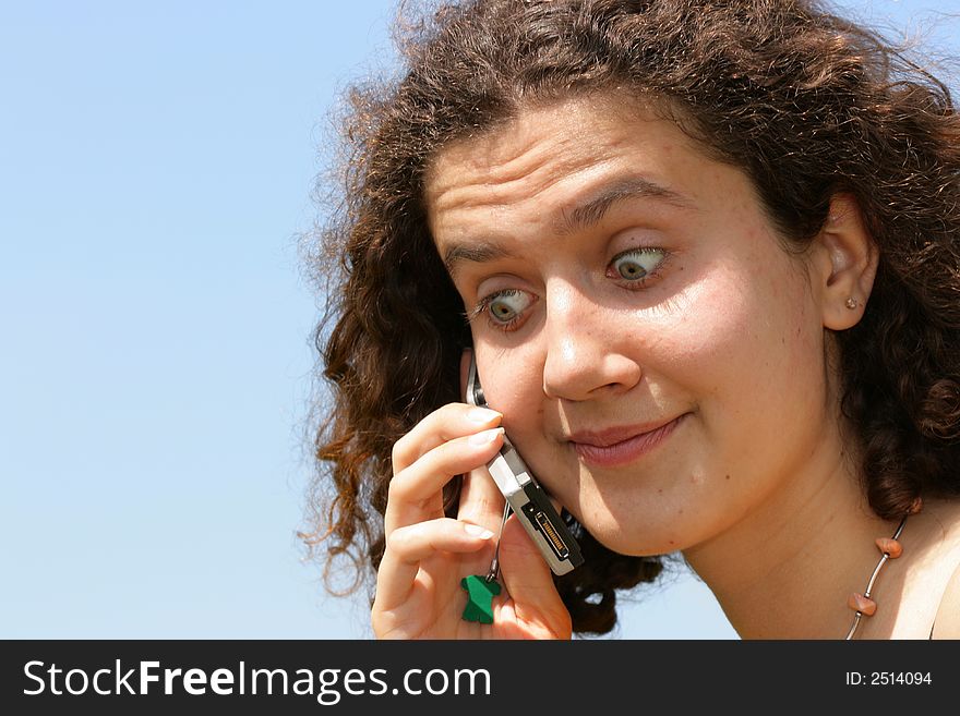 Amazed girl with cell phone against a blue sky