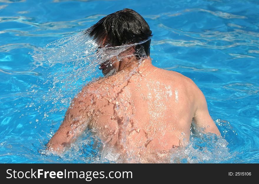 A man shaking of water after swimming competition in bright blue water