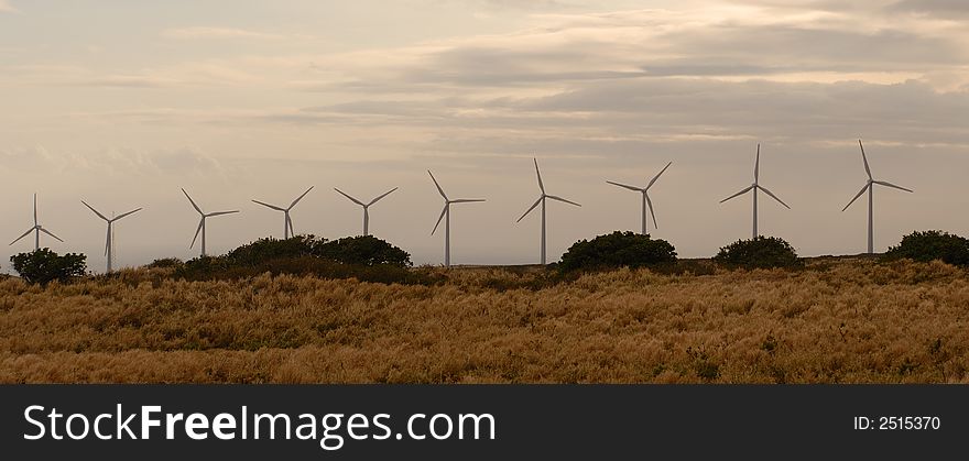 Line of wind power generators on the sky background