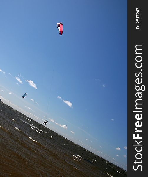 Bold kitesurfer is jumping in the blue sky. Bold kitesurfer is jumping in the blue sky