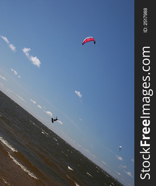 Bold kitesurfer is jumping in the blue sky. Bold kitesurfer is jumping in the blue sky