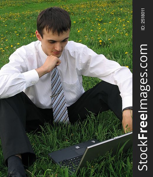 Businessman with laptop sitting on the grass
