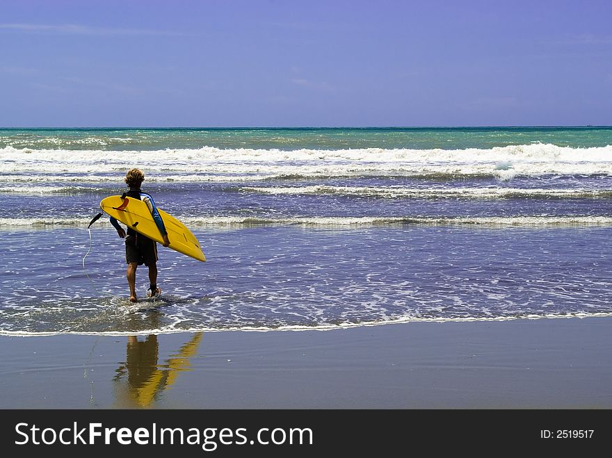 A surfer  enter into the rough sea, ready to surf. A surfer  enter into the rough sea, ready to surf.