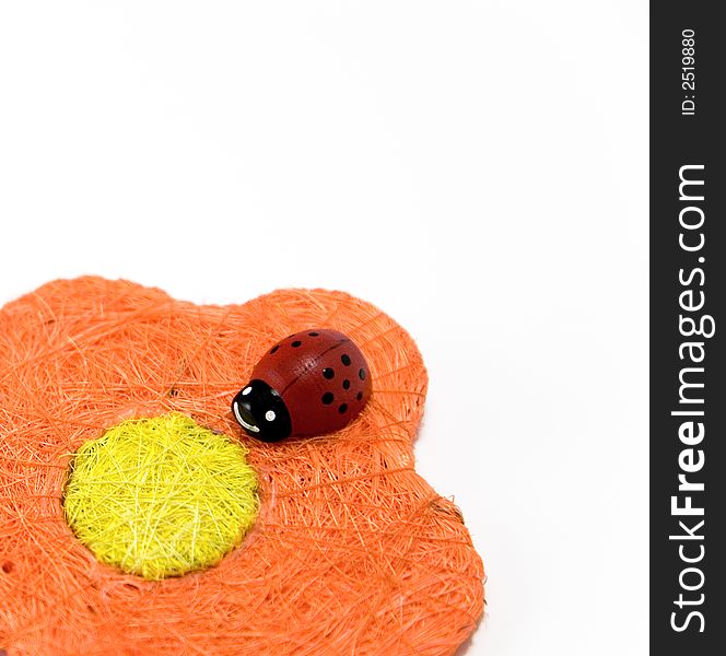 Red wooden ladybird on an orange artificial flower. Red wooden ladybird on an orange artificial flower