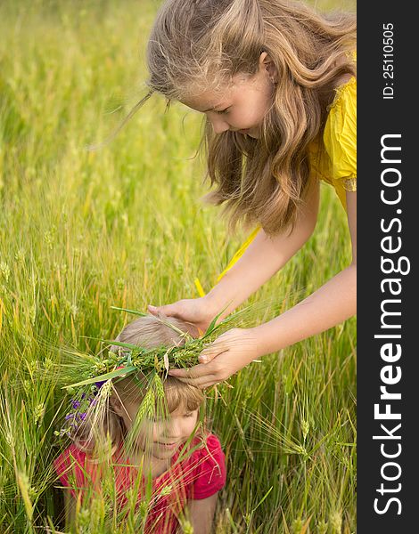 The older sister wears a wreath of the wheat on the head of the younger sister. The older sister wears a wreath of the wheat on the head of the younger sister