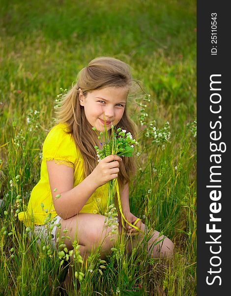 Sweet blonde little girl smelling field flowers on the meadow. Sweet blonde little girl smelling field flowers on the meadow