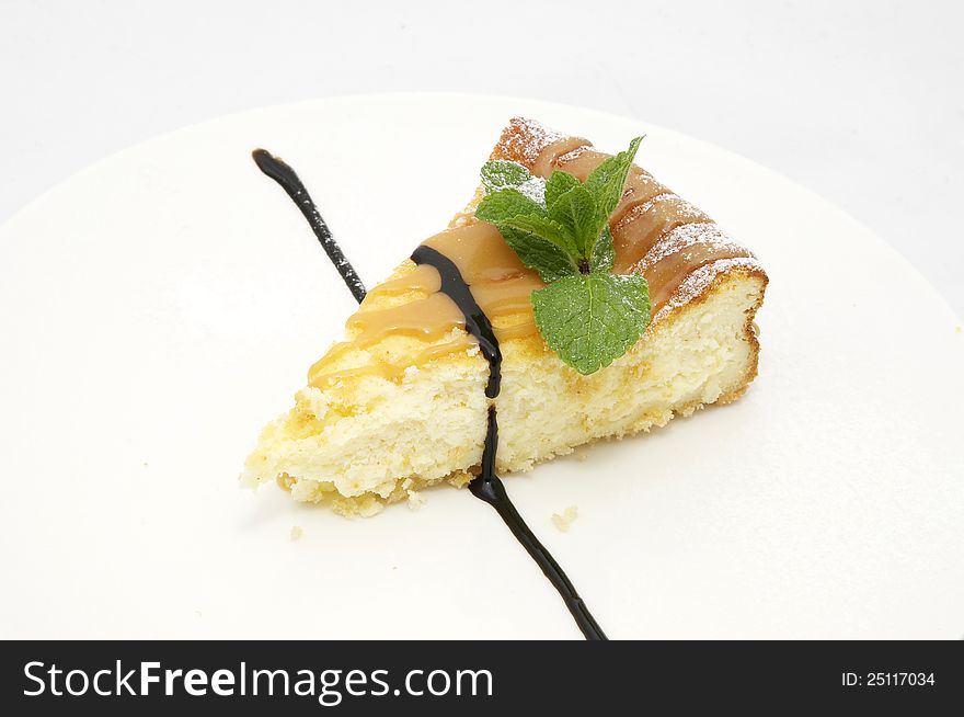 A piece of cheese cake decorated with mint leaves. A piece of cheese cake decorated with mint leaves