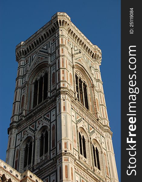 The bell tower of the Santa Maria Del Fiore cathedral (the Duomo) of Florence, Italy, set against a deep blue sky, which makes its white, green and pink marble sparkle in the sun. The bell tower of the Santa Maria Del Fiore cathedral (the Duomo) of Florence, Italy, set against a deep blue sky, which makes its white, green and pink marble sparkle in the sun.