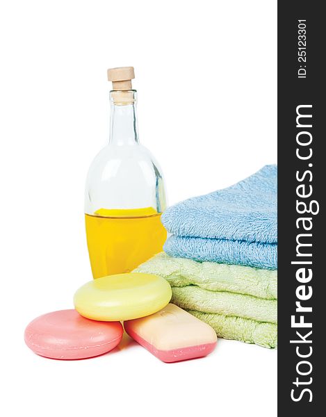 Three varicoloured bars of soap, two by a towel pile and massage oil. Three varicoloured bars of soap, two by a towel pile and massage oil