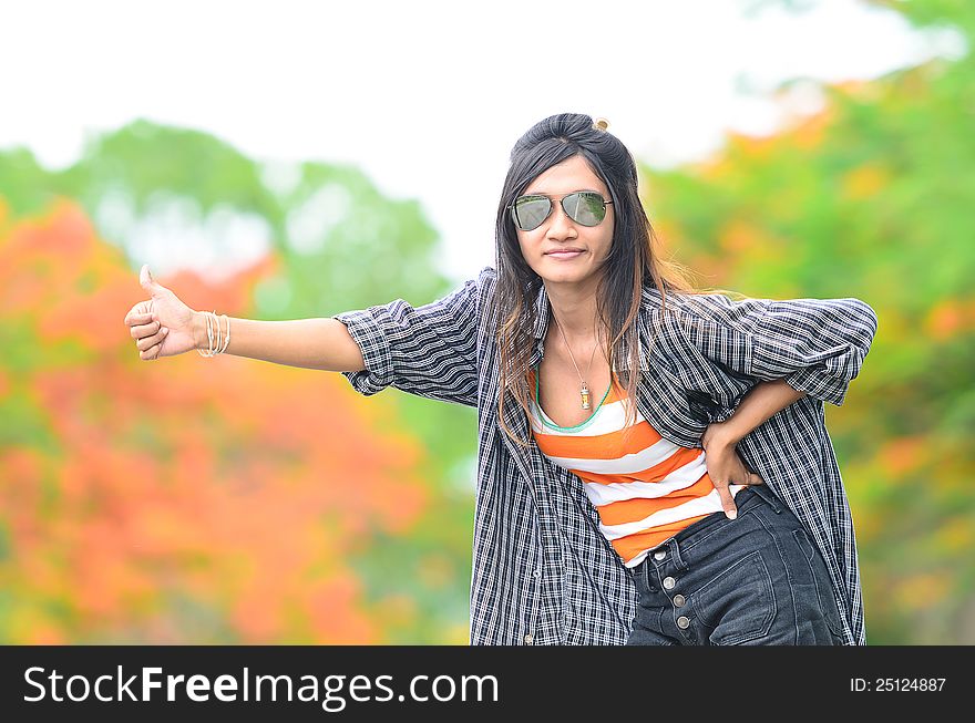 An asian attractive delight girl travelling by thump up with casual sexy wear on blur forest background. An asian attractive delight girl travelling by thump up with casual sexy wear on blur forest background