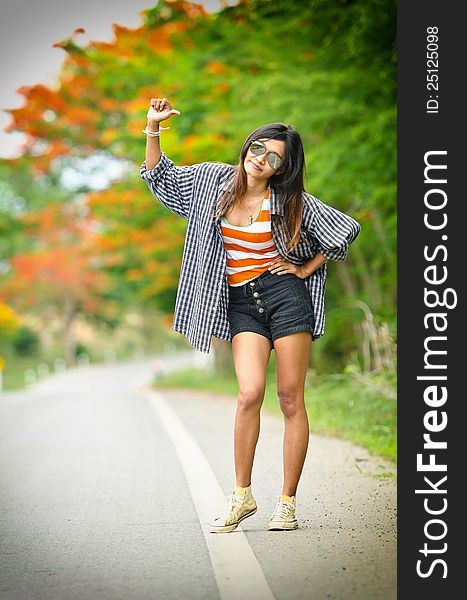 An asian attractive delight girl travelling by thump up with casual wear on blur forest background. An asian attractive delight girl travelling by thump up with casual wear on blur forest background