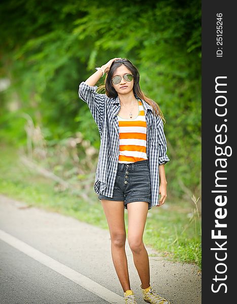 An asian attractive delight girl travelling by thump up with casual sexy wear on blur forest background. An asian attractive delight girl travelling by thump up with casual sexy wear on blur forest background