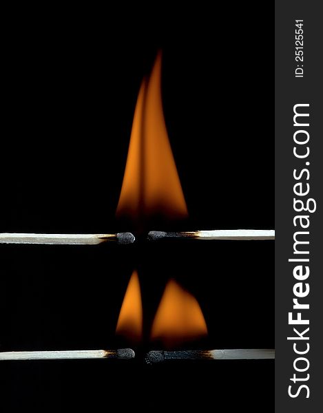 Burning matchstick on black background