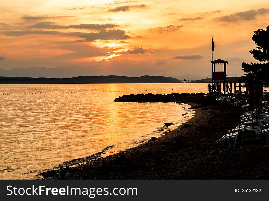 Evening sunset on beach with sun beds and guardian towers