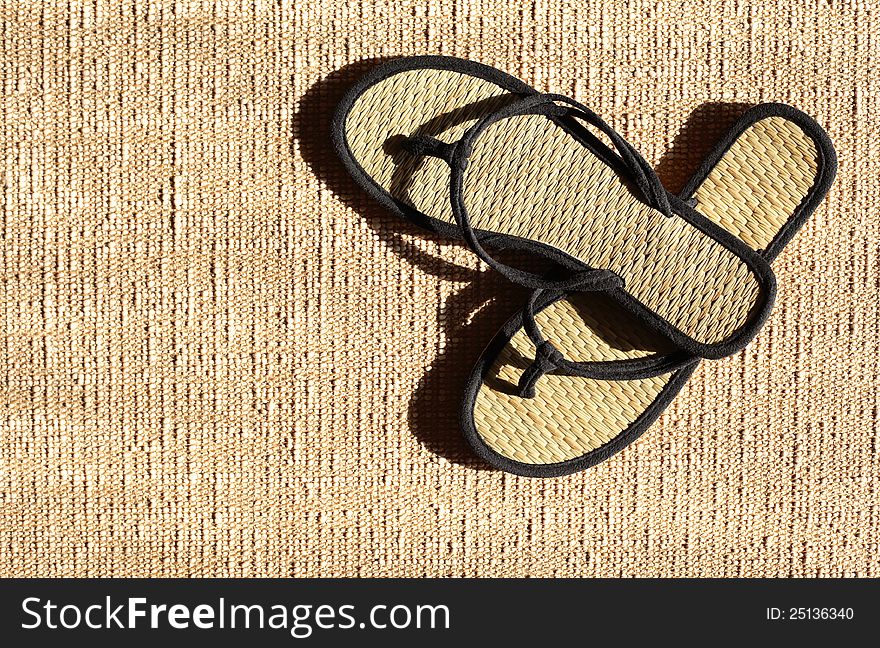 Pair of female summer thongs on jute surface under sunbeam. Pair of female summer thongs on jute surface under sunbeam