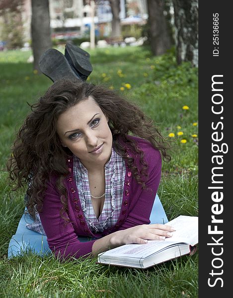 Portrait of young female student in park holding a book. Portrait of young female student in park holding a book