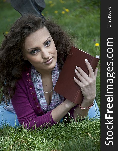 Portrait of young female student in park holding a book. Portrait of young female student in park holding a book