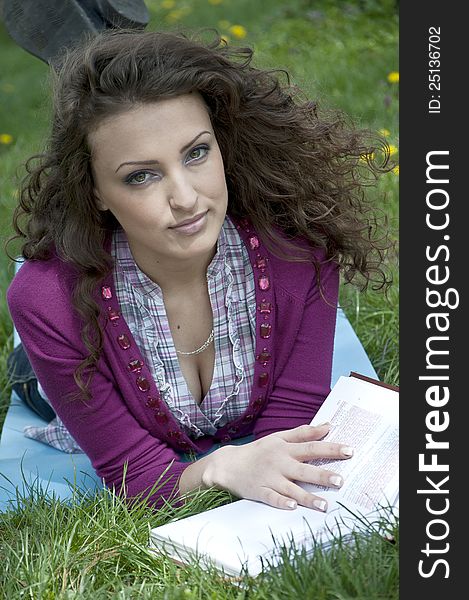 Portrait of young female student in park while reading a book. Portrait of young female student in park while reading a book