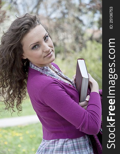 Young woman in park holding a book. Young woman in park holding a book