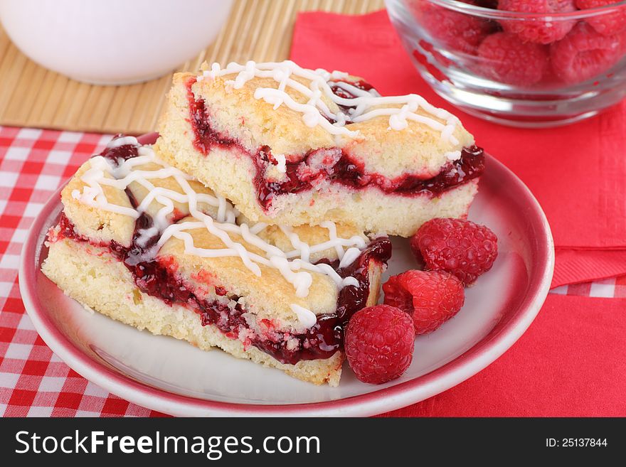 Two raspberry bars and berries on a plate