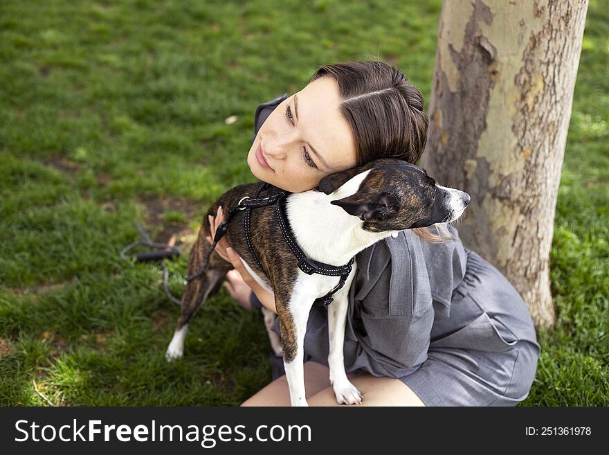 Optimistic woman in grey suit smiling and playing with dog.