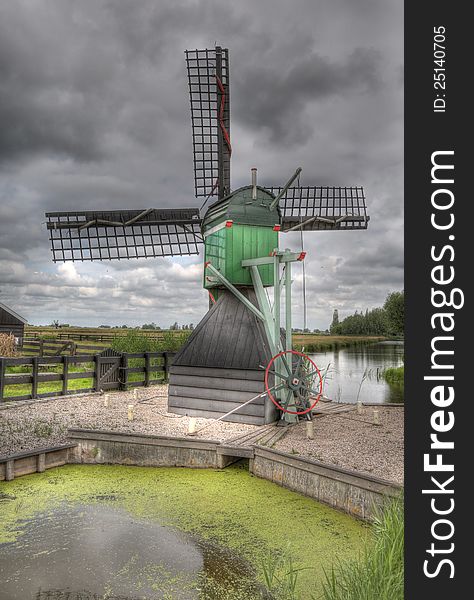 A windmill in Amsterdam with a pond in the foreground