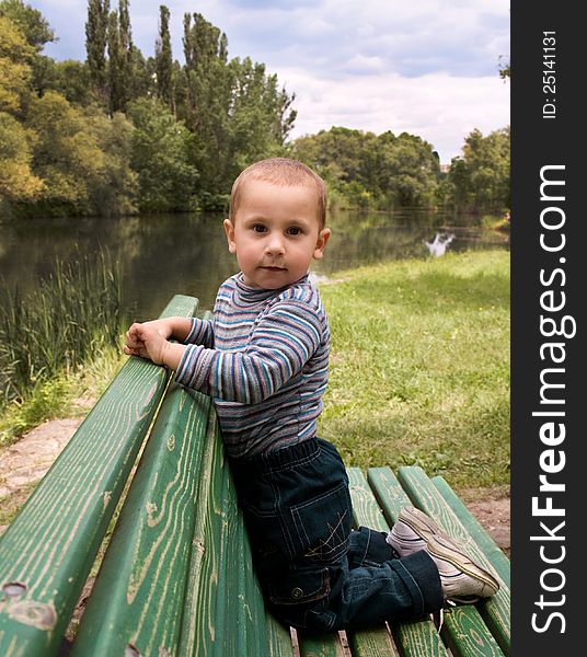 Boy sits on a park bench in the open air. Boy sits on a park bench in the open air