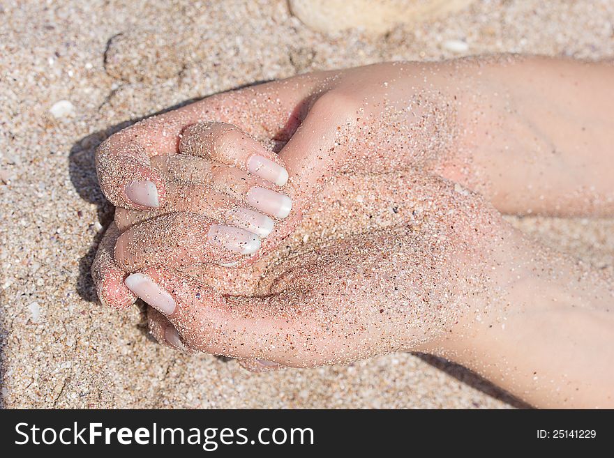 Nice hands with manicure in sand