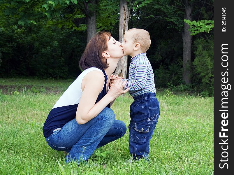 Mother kissing baby outdoors in the park. Mother kissing baby outdoors in the park