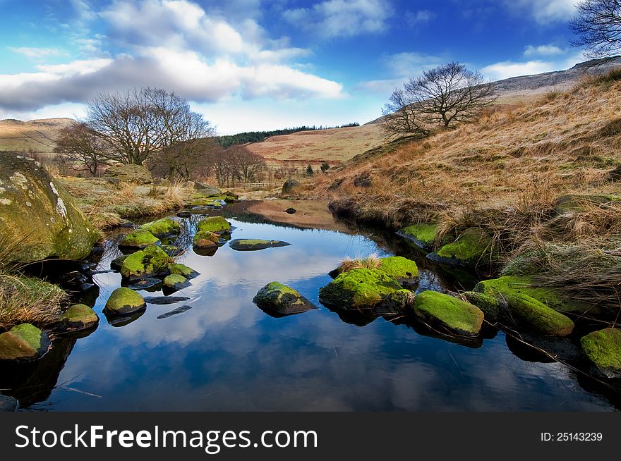 A beautiful landscape with blue sky and green stones in the foreground. This landscape is near dovestone reservoir in the Peak District. A beautiful landscape with blue sky and green stones in the foreground. This landscape is near dovestone reservoir in the Peak District.