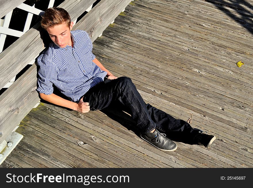 Teenager Sitting Along The Side Of A Bridge