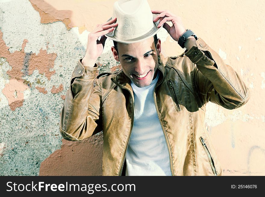 Portrait of a handsome young man smiling with a hat in urban background. Portrait of a handsome young man smiling with a hat in urban background