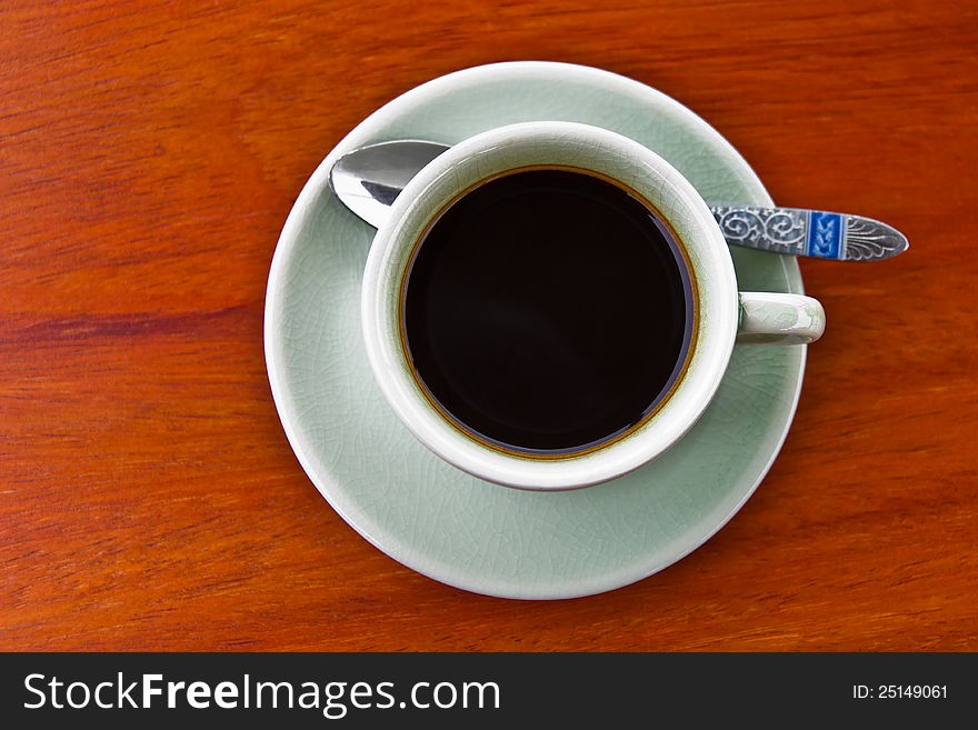 A cup of hot espresso on wooden table, top view